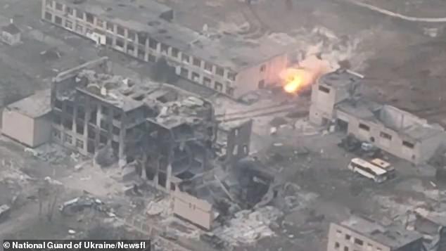 A Ukrainian tank scores a direct hit against a Russian BMP armoured personnel carrier (right of shot) from several hundred metres, with the shot passing through the burnt out husk of a building (left of shot)