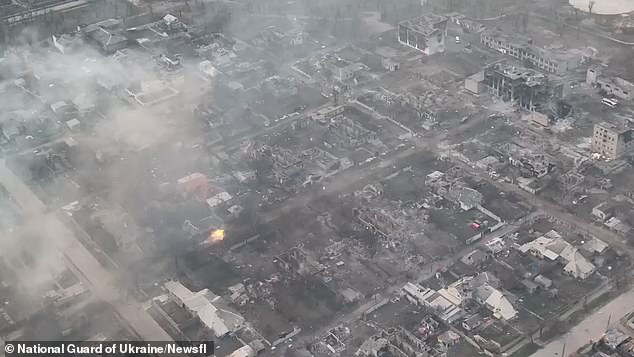 In this wide shot, the muzzle flash of the Ukrainian tank's cannon can clearly be seen near the bottom left, hitting its Russian target in the upper right of the shot with a direct hit that passes through the partially destroyed building just before it